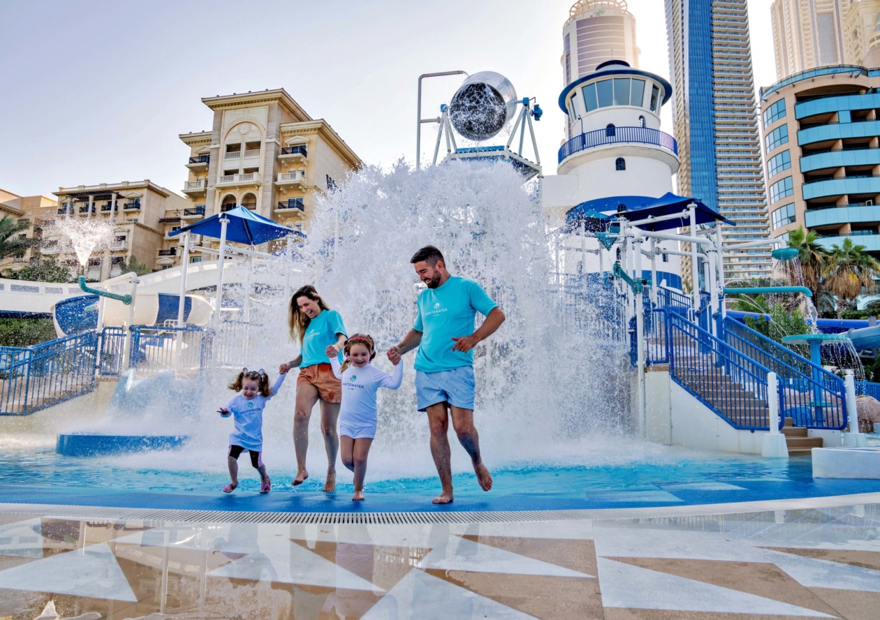 A family of four is enjoying the traditional navy-colored water facilities, with buckets pouring water from above