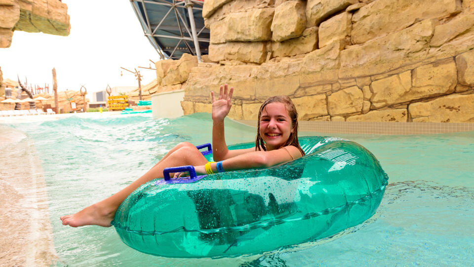 A girl lying on a lifebuoy smiling and waving hello