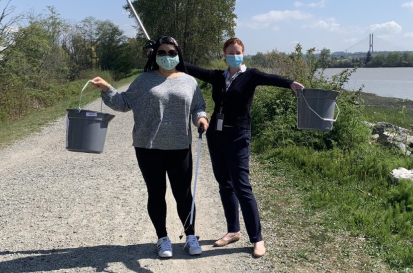 Two women holding plastic bucket and trash picker
