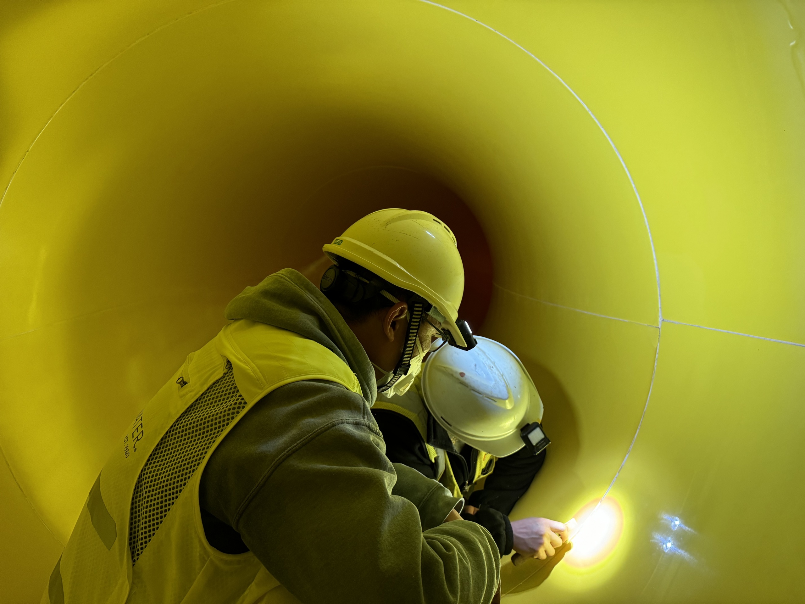Two men inside a water slide flume inspecting
