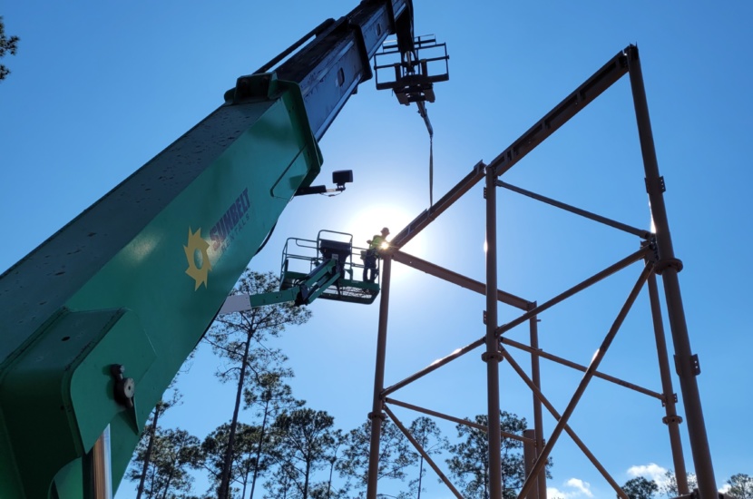 A worker is using machinery to carry out construction at a height